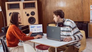 A man and a woman in a music studio using two MSI laptops.