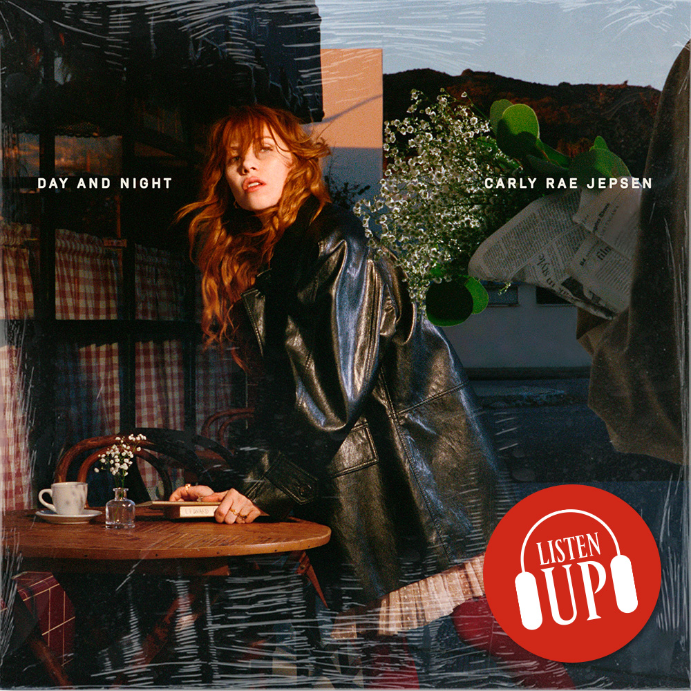 Carly Rae Jepsen poses in a long leather trench coat leaning over a table with a collage behind her on the cover of her album day and night 