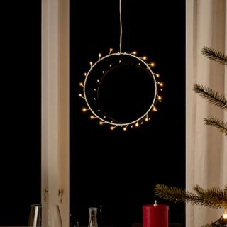 An STRÅLA LED pendant lamp in a window on a dark night