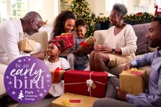 A family sat on a sofa opening Christmas presents, with a Park Christmas Savings logo on the top