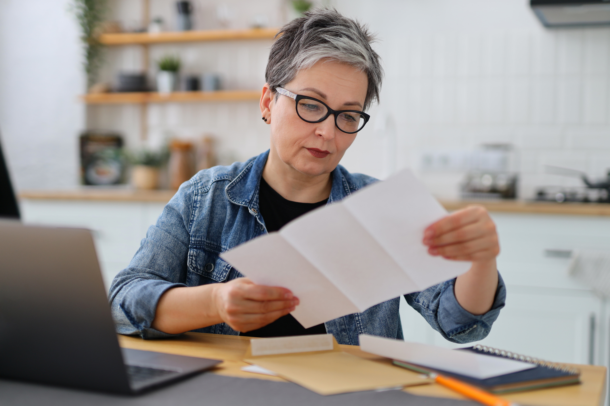 Woman in glasses reading the bill in the kitchen