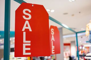 Two large sale signs displayed in a clothing store.