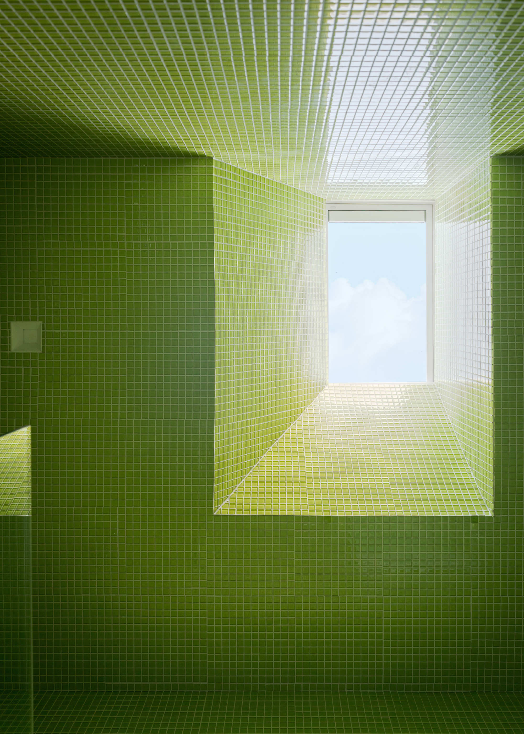 A lime green tiled bathroom with a skylight