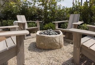 round limestone fire pit with adirondack chairs by Garden Studio Design