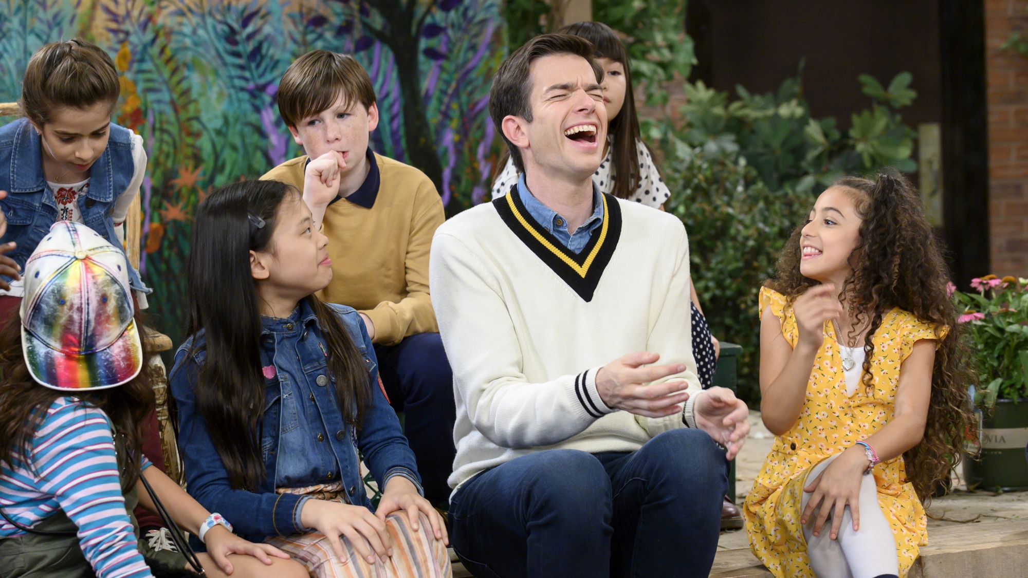 children seated around John Mulaney in John Mulaney & The Sack Lunch Bunch, one of the best family movies on Netflix