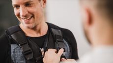 Man has clips on a vest done up by another man
