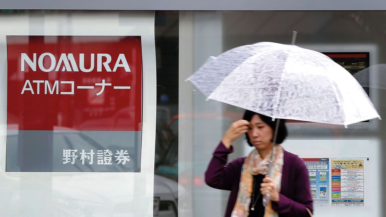 Pedestrian walking past a Nomura bank branch