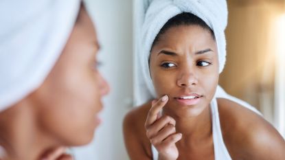 woman checking skin in bathroom mirror