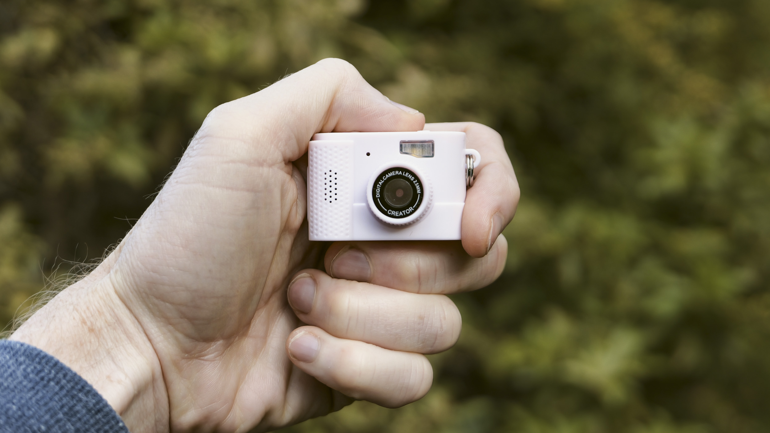 Miniature pink keychain camera, the 'Photo Creator Mini Digital Camera series 3', in user's hand