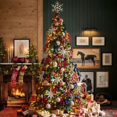 A Christmas tree next to a fireplace layered with Christmas decorations including photo frame ornaments from Pottery Barn