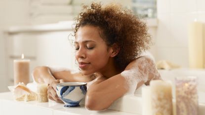 Woman in bath with cup of tea pampering