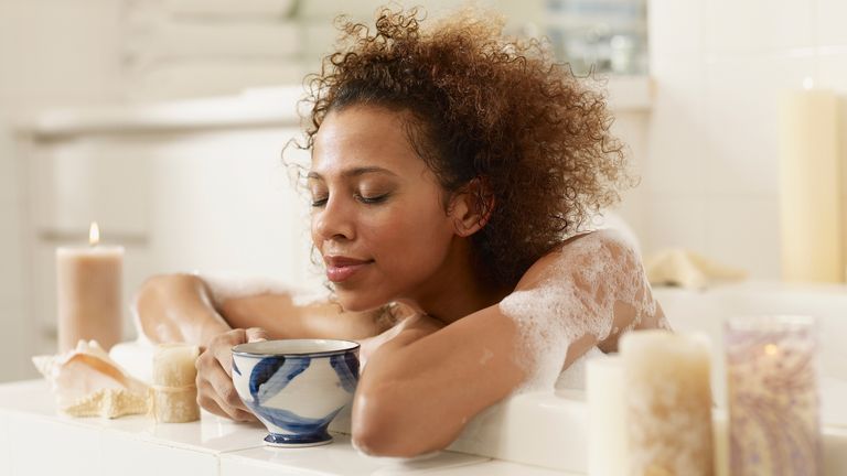 Woman in bath with cup of tea pampering
