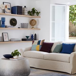 Cream coloured sofa with coloured cushions in living room, shelving display