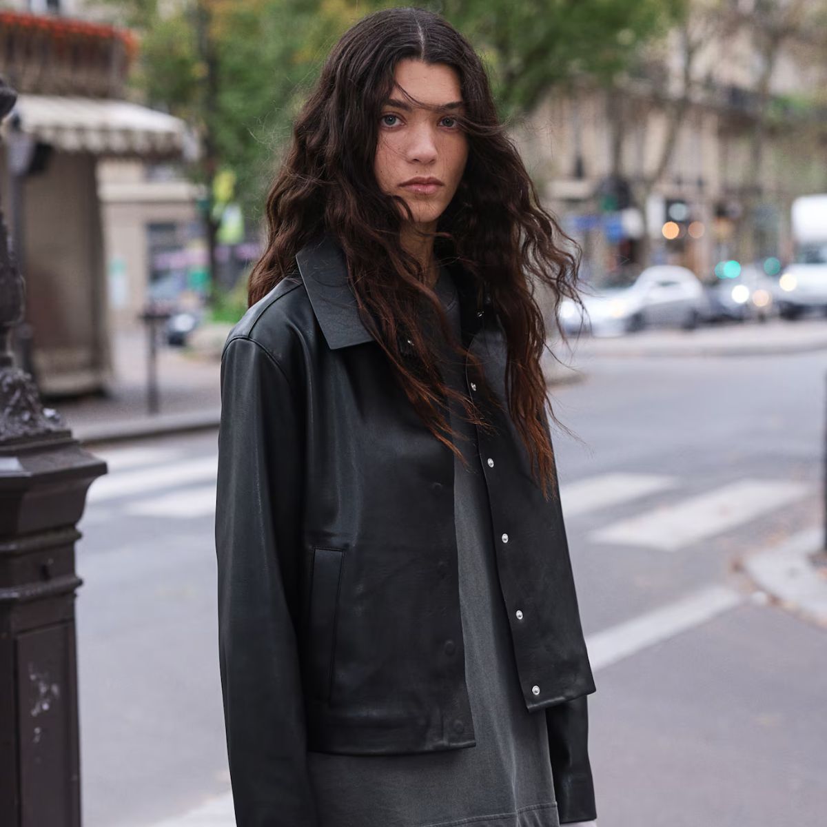Woman wears black leather look jacket and grey top