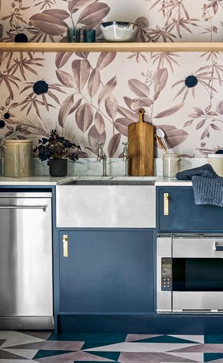 stainless steel sink in kitchen with blue cabinetry and pink patterned wallpaper