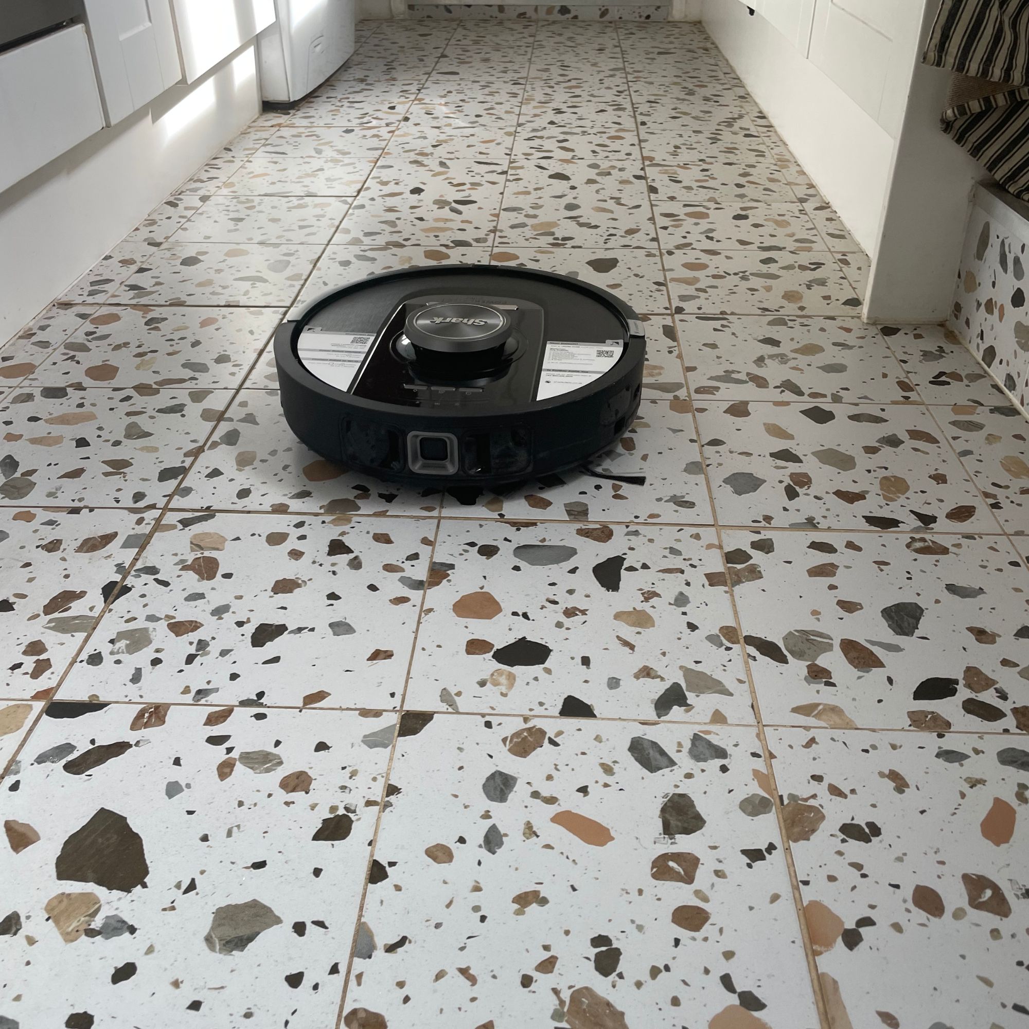 Shark PowerDetect NeverTouch Robot Vacuum in a kitchen with terrazzo tiles on the floor