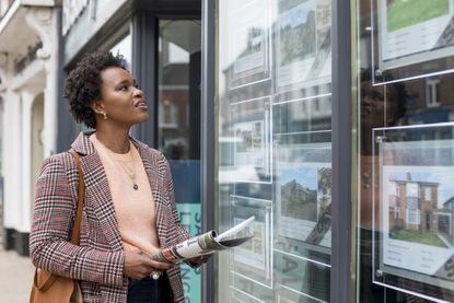 Woman looking in a shop window of an estate agent's