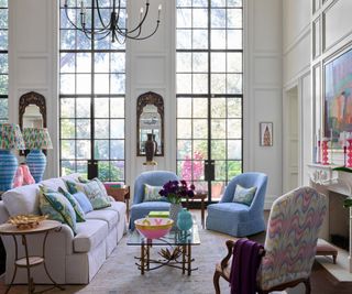 large living room with tall windows, white panelled walls, pops pf blue and pink colorful decor