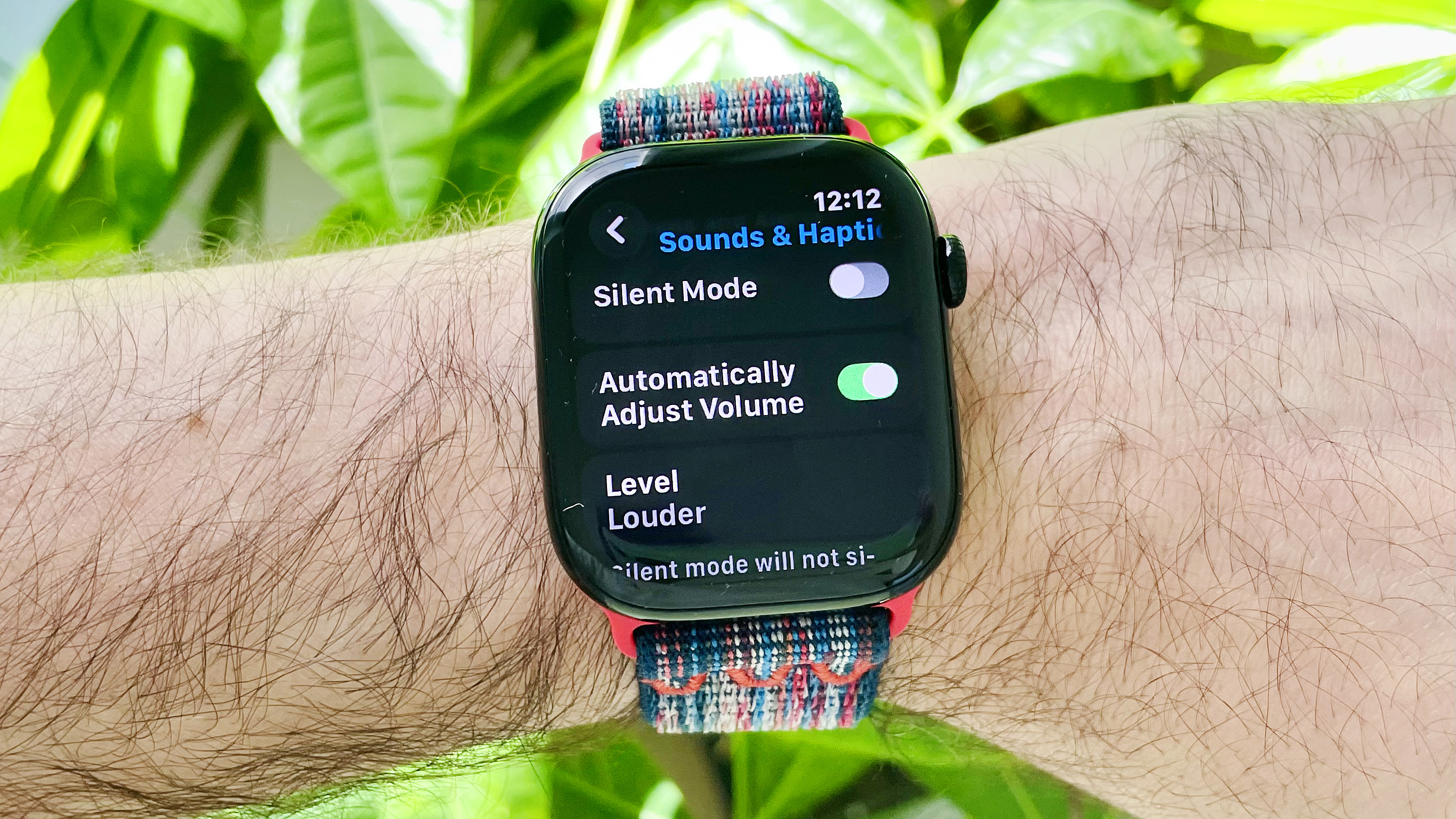 Close-up of a user's wrist wearing the Apple Watch Series 10 running the latest watchOS 26 software. The screen shows the new Automatic Audio Adjustments setting