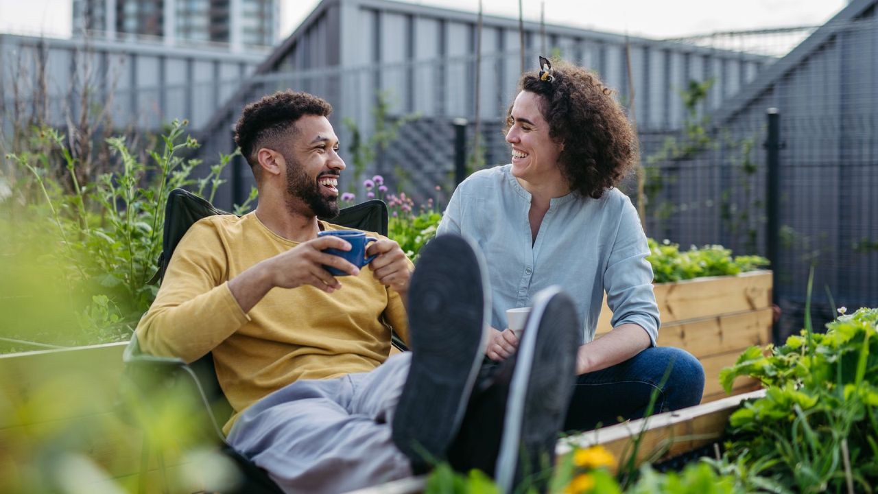 A man and woman laugh in a rooftop garden