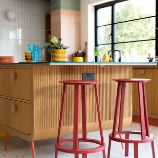 Panelled kitchen island with red bar stools.