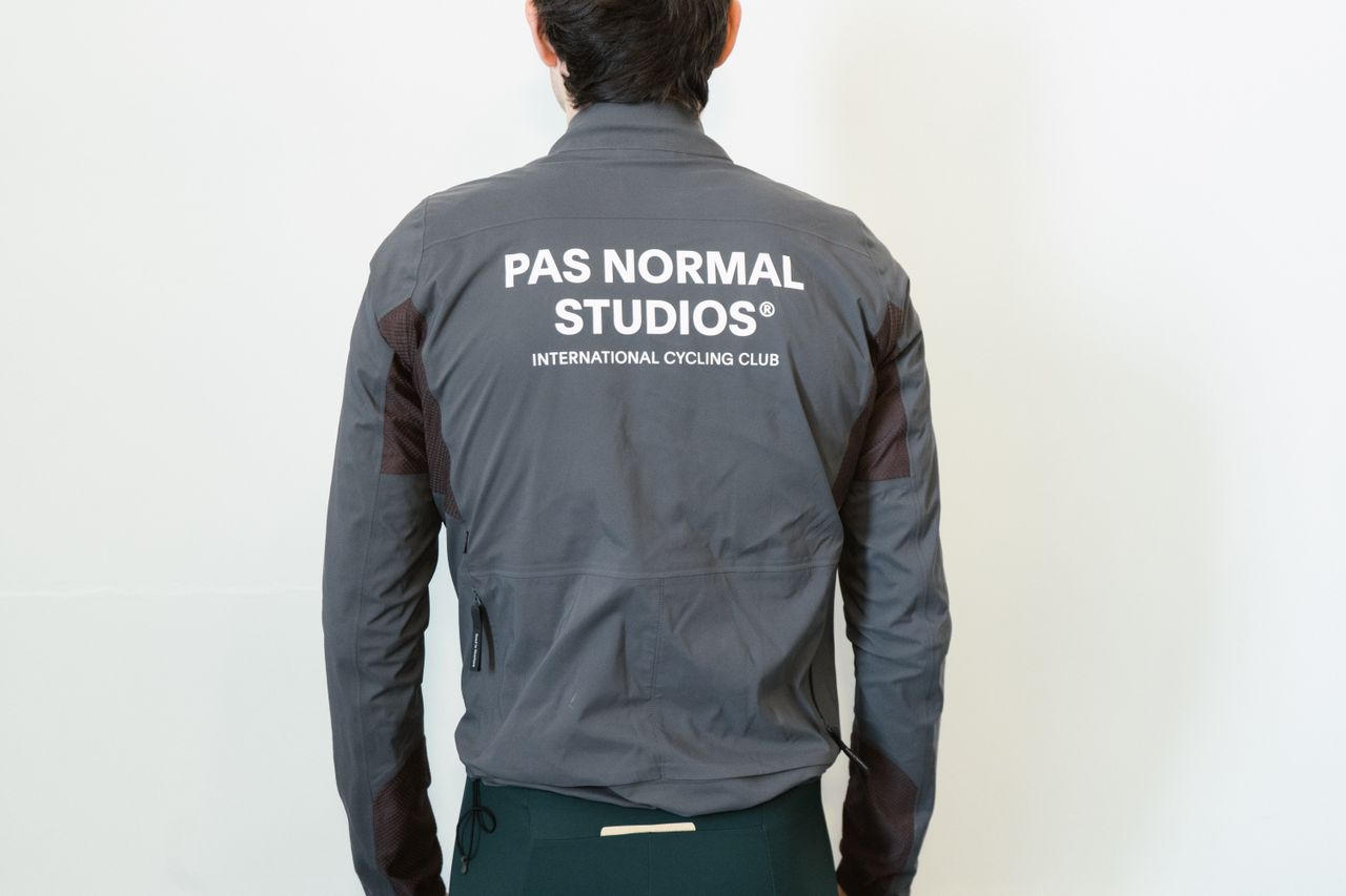 A man in a grey waterproof jacket against a white wall