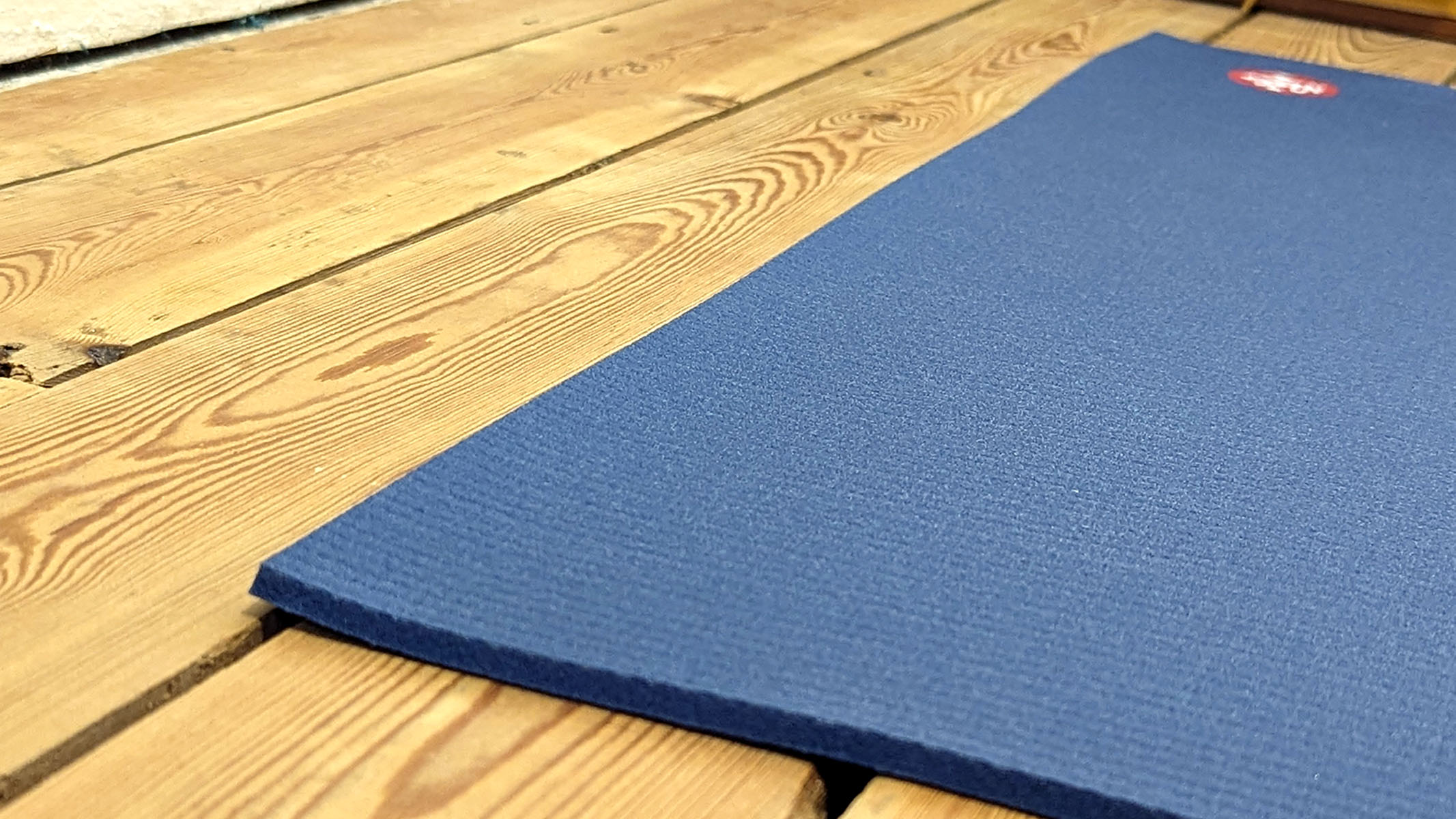 Manduka PRO yoga mat laying flat on wooden floor