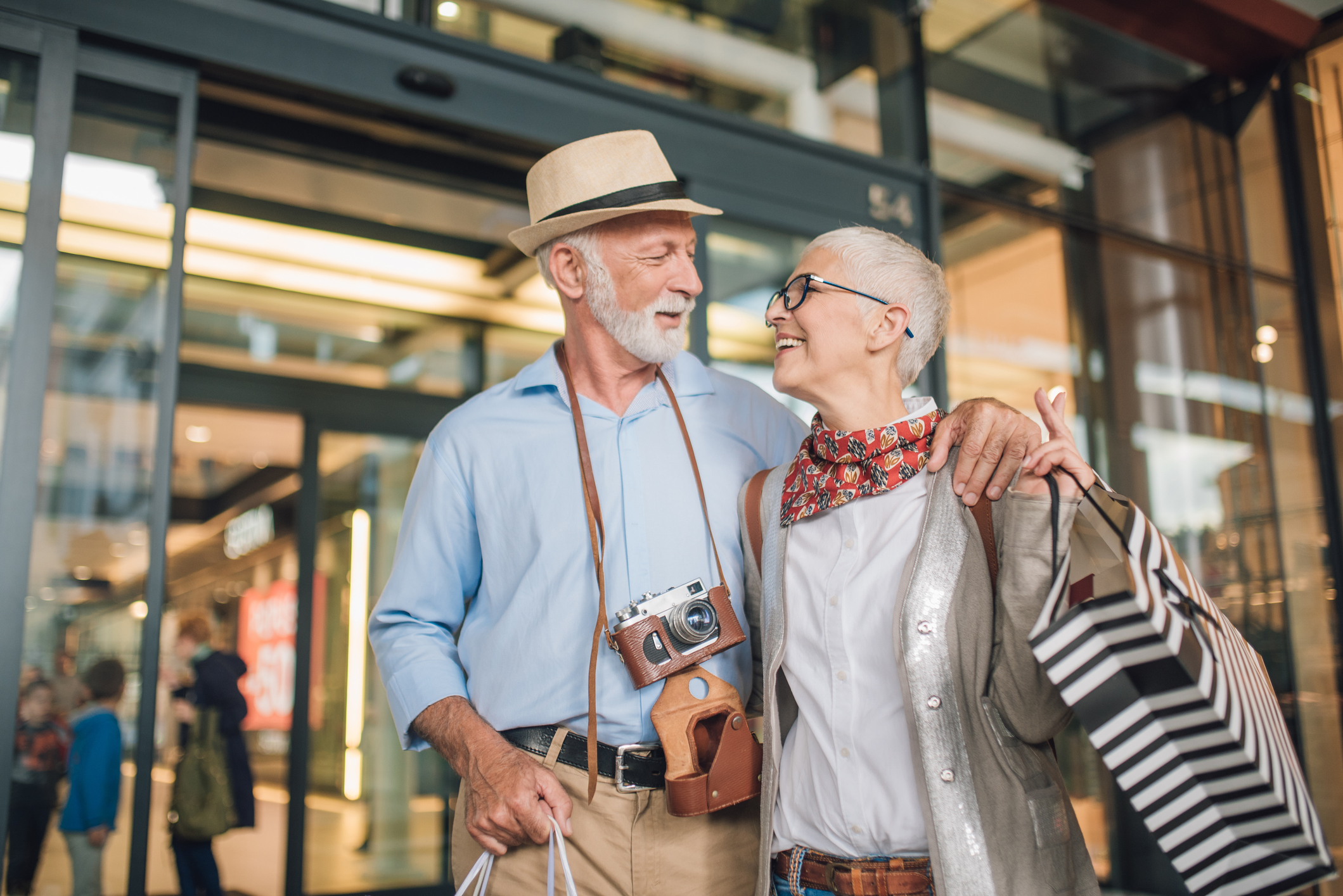 Happy older couple looking at each other while holding shopping bags