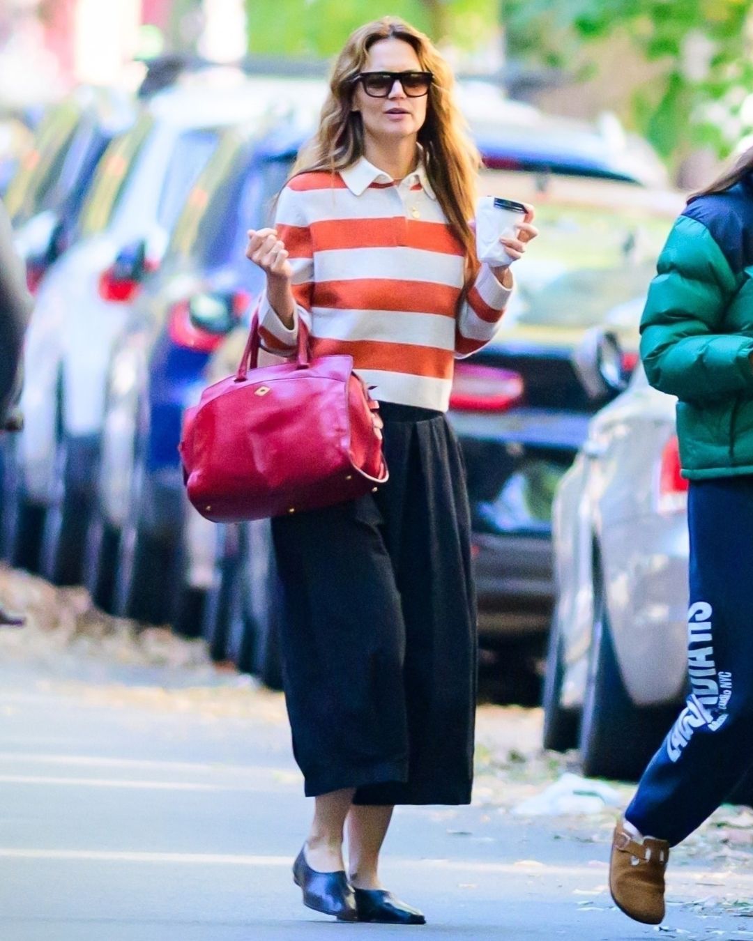 Katie Holmes wears high vamp black flats with black culottes and a striped polo jumper.