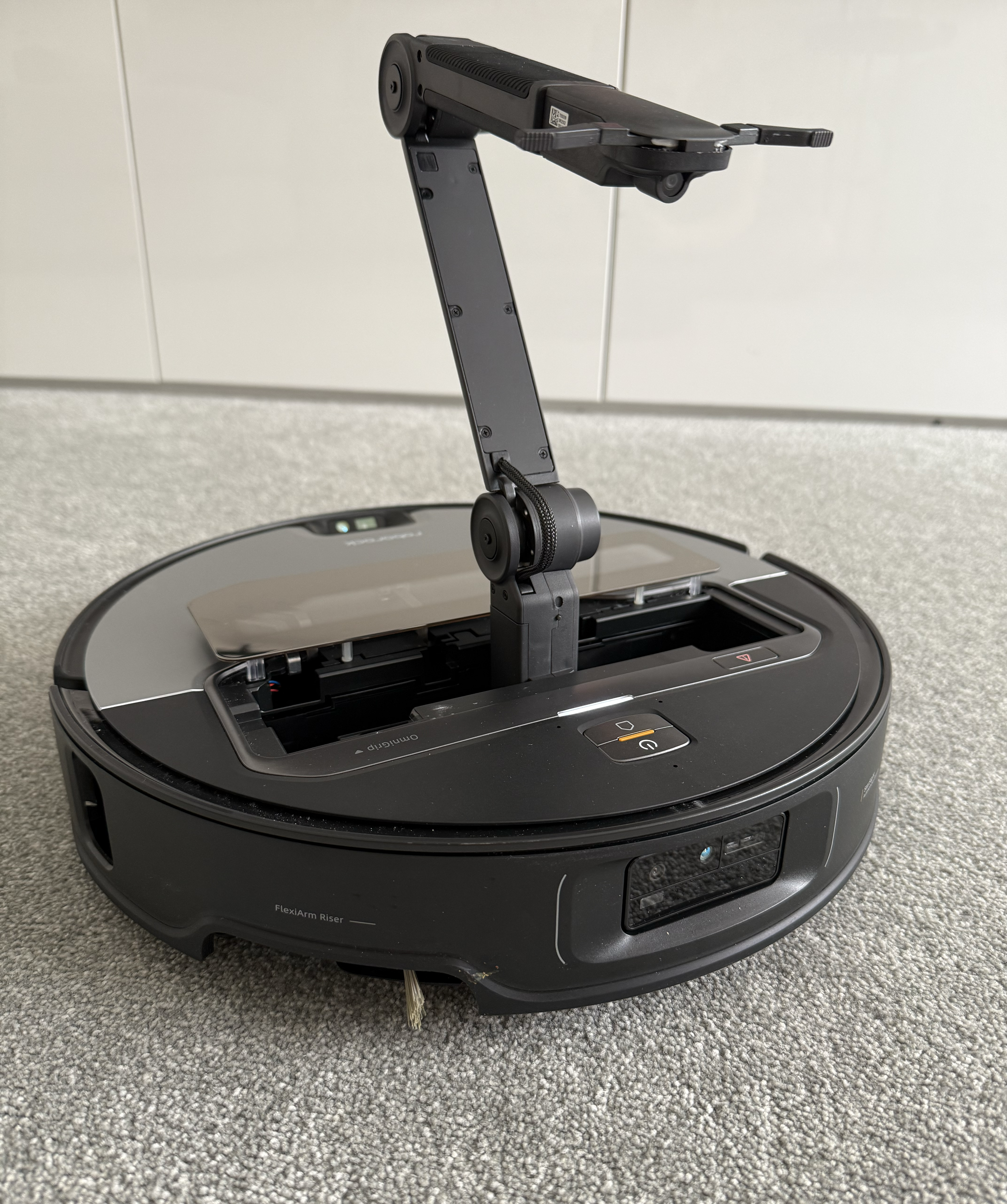 Roborock Saros Z70 on gray carpet showing mechanical arm raised above robot, in Victoria Woollaston's home