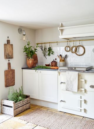 kitchen with white cabinets and white range cooker with brass hanging rail and limestone flooring