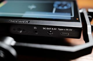 A neewer F500 field monitor's bottom edge, with ports for power and headphones.