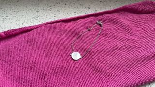 a piece of silver jewelry on a pink microfiber cloth on a kitchen worktop