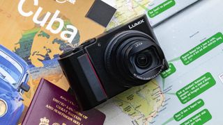 Panasonic Lumix ZS200 / TZ200, una de las mejores cámaras para viajar, sobre una mesa con un mapa y un pasaporte al lado