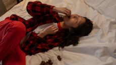 A woman eating chocolates in bed