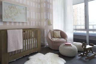 A small nursery with sofas and ottomans and a crib