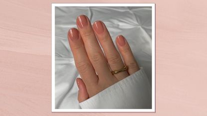 Hand wearing short, square glossy peach-hue nails and a gold ring