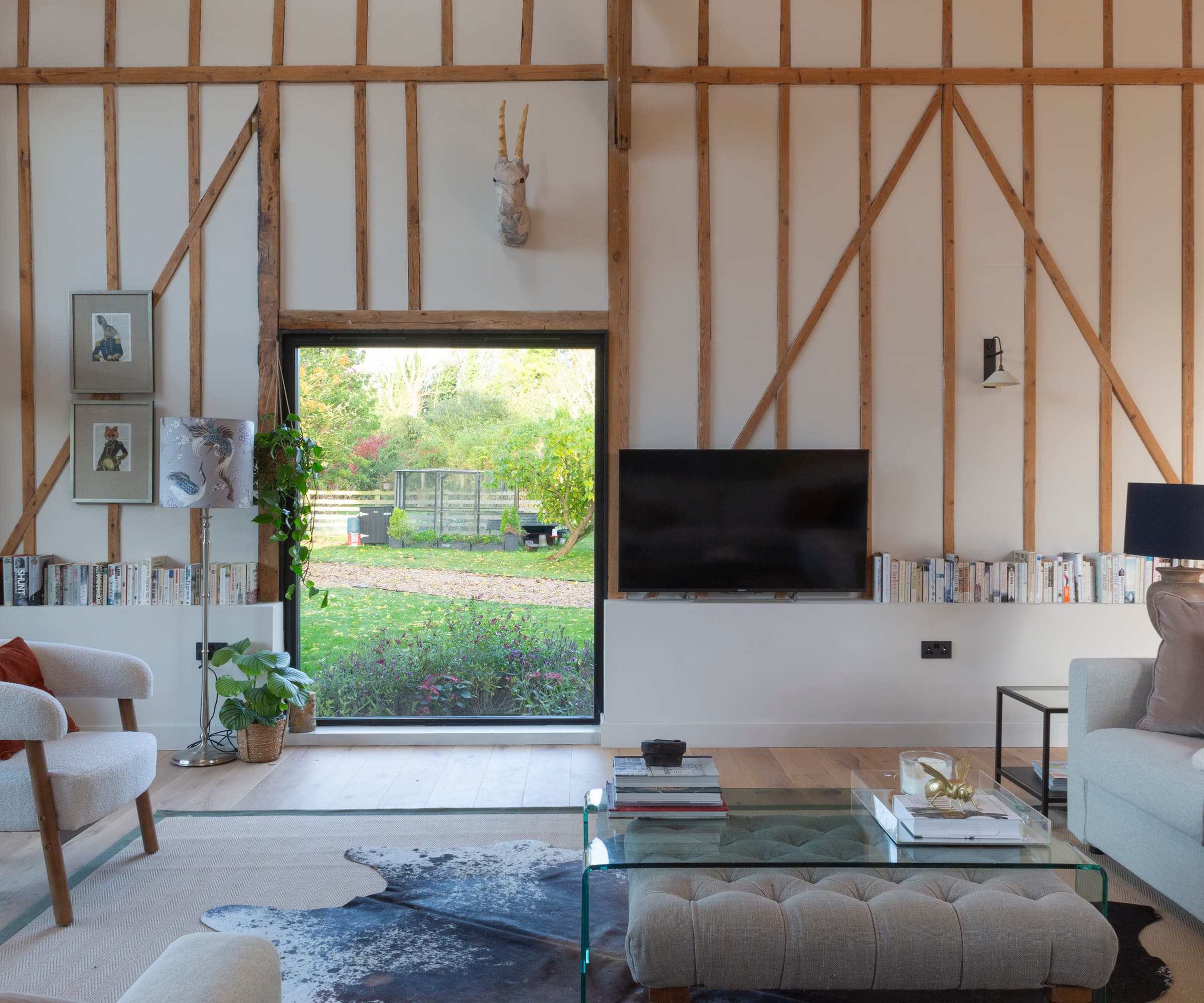 An open plan living room with a glass door and timber framed wall with white plaster