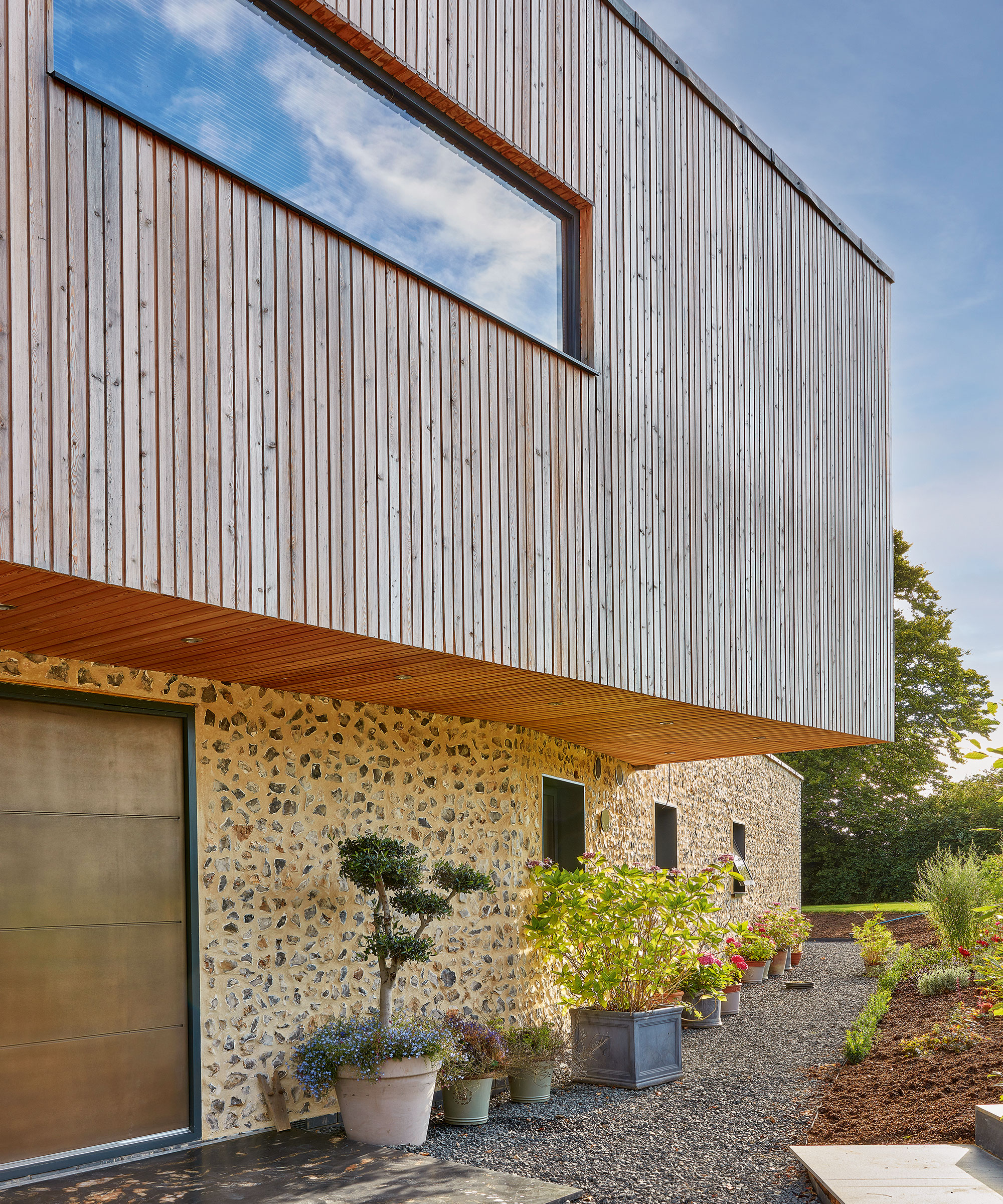 exterior of a modern house with timber cladding on the upper half of the house and stone on the lower half