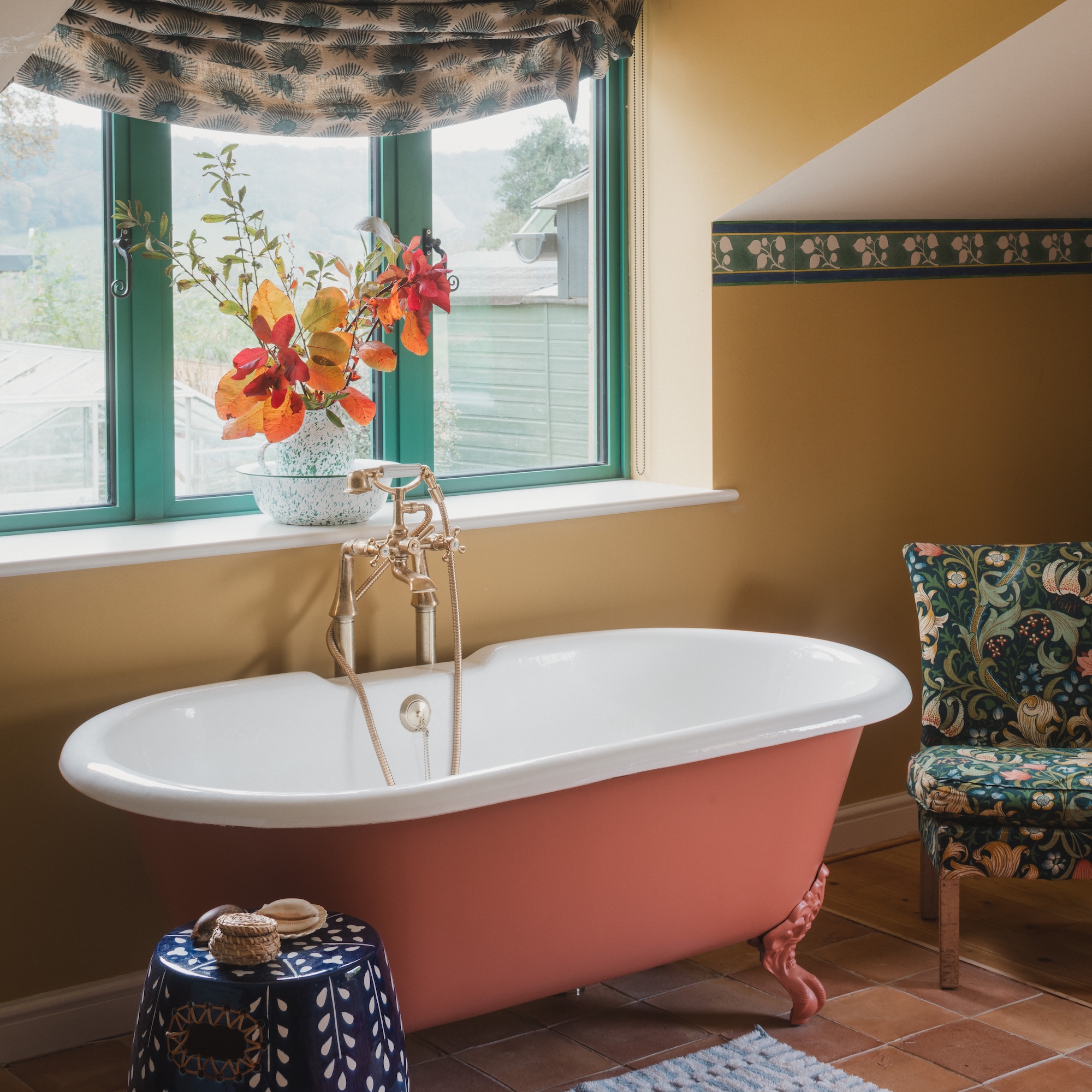 pink-orange freestanding bath with mixer taps in bedroom below window with green painted frames