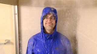 Dan getting wet as part of the REI Rainier Rain Jacket Shower Test