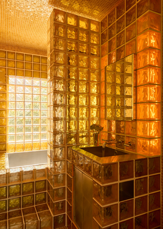 A yellow glass block covered bathroom, with yellow mosaic tile ceiling