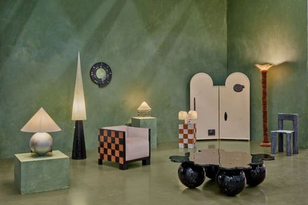 A furniture design installation set inside a green-tinted room features whimsical, sculptural furniture, including pointy standing lamps, spheres-standing coffee tables, and checkered decor.