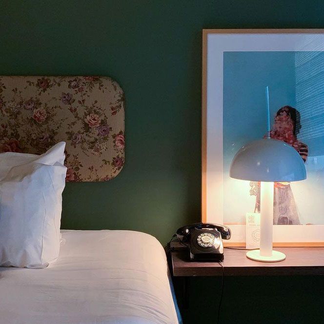 Meja nakas dengan lampu meja biru dan bingkai di samping tempat tidur di apartemen