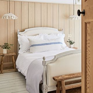Bedroom with vintage look wood and upholstered bed and wood panelled walls