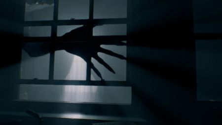 A shadowy hand with long taloned fingers moving past a window in Resident Evil Requiem
