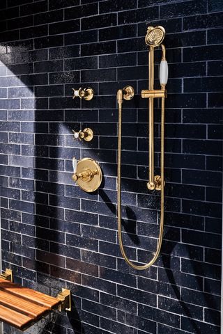 black tiled shower with gold shower head and wooden shower bench