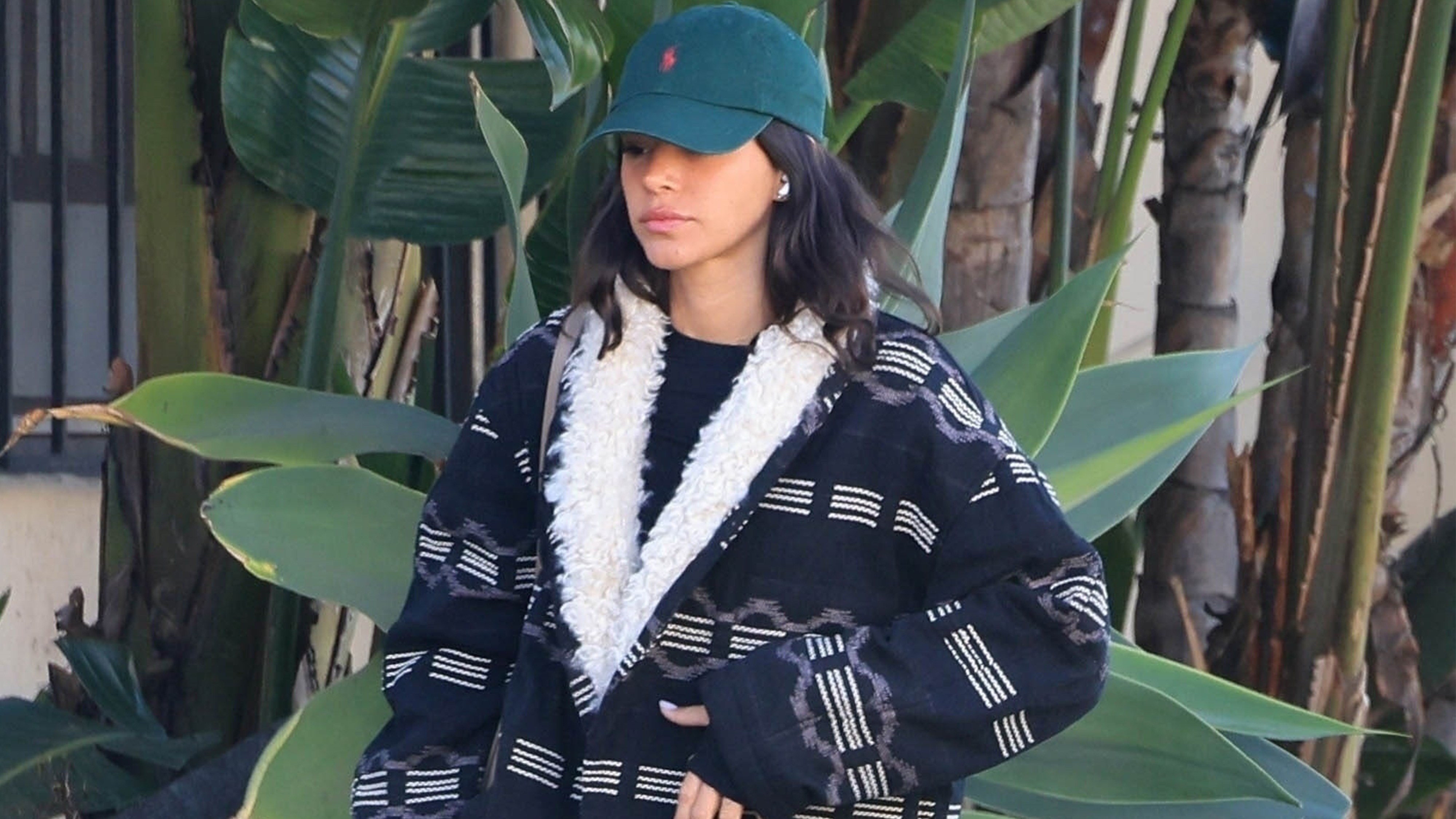 Bruna Marquezine wears a ralph lauren hat and a printed coat with shearling trim.