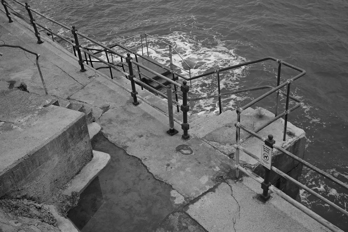 A wave crashing against a seaside walk