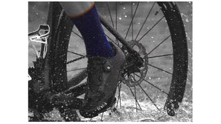 a cyclist riding through a puddle of water with blue socks